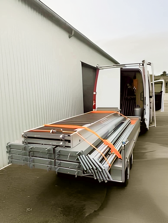 Camion tractant une remorque chargée d’échafaudages pour un chantier de peinture en bâtiment
