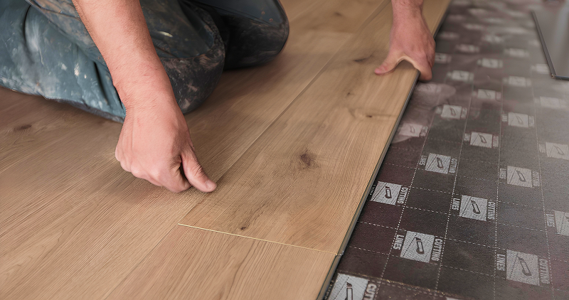 Pose de parquet flottant avec sous-couche isolante sur un chantier propre et bien préparé, illustrant le soin apporté à la protection des sols et à la qualité d'exécution